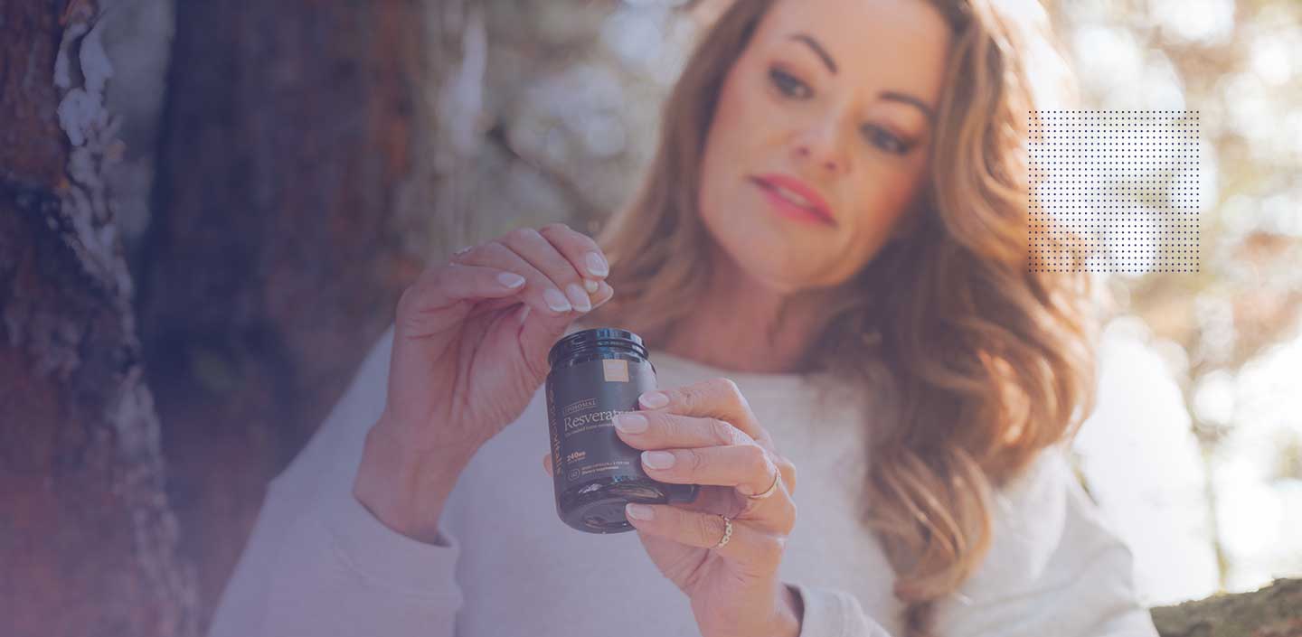 O femeie ține în mână o sticlă de capsule de resveratrol, prezentând potențialul acestuia pentru îngrijirea pielii.