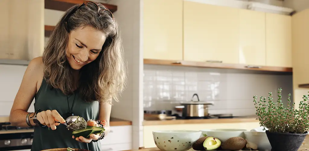 Donna sorridente in cucina che prepara un avocado